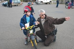 Above: Cook County Deputy Leif Lunde gives eager Lomer Eich instructions as Lomer prepares to navigate the difficult turns in the bicycle course. Right: At 22 months, Ruby Hawkins was the youngest rider to take part in the Bike Rodeo.