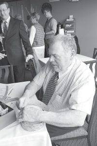 Above: Spenser Motschenbacher was the man to see for chances at the raffle, which included many wonderful items donated to support the community school. Right: The auctioneer for the evening was once again Bill Hansen of Tofte, pictured here trying to decide which dessert would be more delicious.