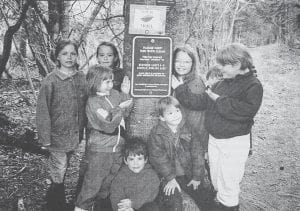 “PLEASE KEEP THIS RIVER CLEAN” proclaims the newly-posted sign at the beginning of the Kadunce River Hiking Trail. The sign was awarded by the Minnesota Department of Natural Resources in appreciation of the efforts of this group of happy youngsters who did spring clean-up on the trail in 1997. Shown are, back row from left, Regina Dolan, Kali Hawkins, Gwen Danfelt-Martin, Corrie Lewis and Amanda Drake; front row, Jordi Saethre and Brennan Hawkins; and seated, Miles Drake. The photo appeared in the June 23, 1997 edition of the Cook County News-Herald.