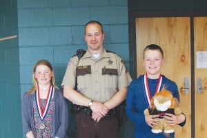 Deputy Ben Hallberg with the winners of the D.A.R.E. essay contest winners. Malin Anderson (left) and Noah Furcht summed up what they learned in D.A.R.E. and its decision-making model in their essays which they read in front of the D.A.R.E. graduation audience. They received D.A.R.E. medals and their own Darren the D.A.R.E. lion mascots.