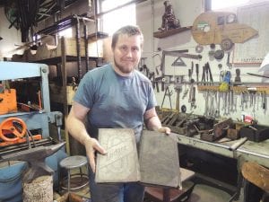 Drew Johnson, who is inventorying the artifacts in the old Bally Blacksmith Shop, shows off a treasure that was found in the loft of the wooden building—a business ledger from 1920. This will be invaluable as the historical society studies what work was conducted and for whom.