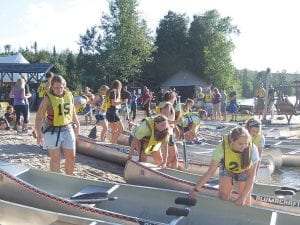 The Gunflint Canoe Races were once again a fabulous fundraiser for the Gunflint Trail Volunteer Fire Department—and they were fun for all involved. Above: It looks a little chaotic as canoes are launched! Right: Elsa Lunde of Grand Marais was the lucky winner of the grand prize, a bright red Wenonah Spirit II Royalex canoe. She is pictured here with her parents, Leif and Sissy Lunde.