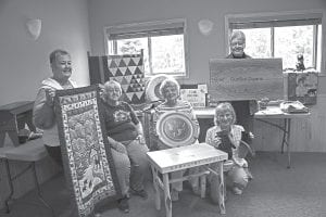 MidGunflint Trail residents are excitedly preparing for the August 7 auction, flea market, boutique, and quilt raffle. The Mid-Trail Quilters are pictured here with some of the items that will be offered. (L-R) Carol Stockman, Eleanor Lease, Lee Zopff and Keitha Herron (kneeling), Sue Sutphin.