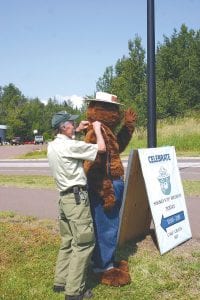 Pete Igoe adjusts Smokey ’s shoulder straps as Smokey waves at passersby. At age 70 Smokey isn’t as flexible as he was when he was a young cub, and he sometimes needs help to get dressed.