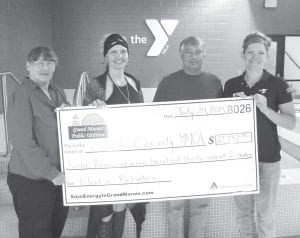 Jan Smith (left), Grand Marais Public Utility Commission secretary, presents a “big check” to the Cook County Community YMCA. Accepting the energy efficiency rebate check were (L-R) Cook County Commissioner Heidi Doo- Kirk, County Maintenance Director Brian Silence and Colette Mueller, YMCA associate executive director.