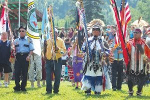 Above: Grand Entry at the Grand Portage Rendezvous Days Powwow is led by veteran warriors bearing traditional staffs and flags. Right: The Rendezvous Days Powwow was co-hosted by the Grand Portage Stonebridge Singers (pictured) and Little Bear from Thunder Bay. The drums alternated singing during the Grand Entries on Saturday and Sunday.