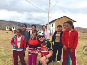 Buck Benson is spending 4½ months pedaling over 4,000 miles through four South American countries. Although he is with a tour group and several riders are racing, Benson and most of the 40 bicyclists choose to stop and look at the scenery, eat the local fare, and as this picture taken in a remote village shows, visit with the children and adults as they pedal into an area.