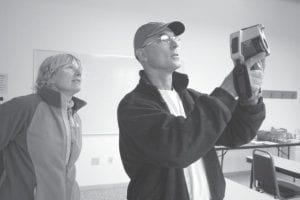 Cook County Higher Education Executive Director Paula Sundet Wolf looks at the infrared camera image Energy Auditor Chris Norman is taking in the CCHE building. This energy audit (through REEP) began the construction process by identifying energy improvements.