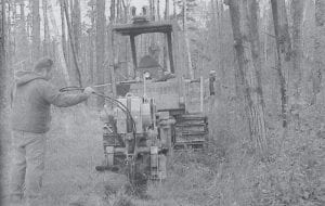 In the caption accompanying this photo from the archives of the Cook County Star, North Superior Ski and Run Club volunteers were encouraged to come out for a trail day and to see the progress toward a lighted Nordic ski trail at Pincushion Mountain in Grand Marais. Arrowhead Electric Cooperative, Inc. and Utilitrax of Ramsey, Minnesota plowed in underground electrical wire on September 14, 2000 on the West Overlook Beginners Loop, a 1.6-kilometer path. Arrowhead provided the materials at cost and Utilitrax provided a four-man crew with a Case Cable-Plow 475 to put the line in.