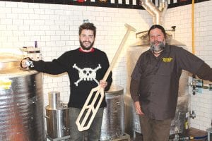 The community has been anxiously awaiting the first taste of beer brewed at the Gun Flint Tavern in downtown Grand Marais. Brewmaster Paul Gecas (left) and Gun Flint Tavern owner Jeff Gecas are as eager as their future customers to start brewing. Paul is ready to stir the first batch with a mash paddle handmade by his dad, Greg Gecas.