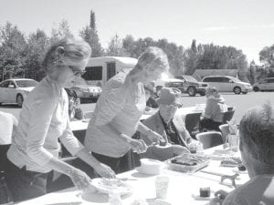 Grandparents Day—and Father Seamus Walsh’s birthday—were celebrated with a barbecue at the Community Center. Joy Carlson dishes up a nice piece of chocolate cake for Father Walsh.