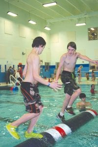 Above left: Dominic Wilson (foreground) and Carson Poupore stared at each other’s feet as they worked the log back and forth in their exciting U-13 match. Above right: Paige Everson (left) and Anna Davenport of the Hudson log rolling team had a great match in the U-13 girls’ division, with Anna taking a narrow win.