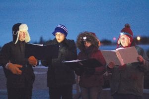 Above left: Kicking off the Christmas parade on November 28 was a tree lighting and beautiful music, thanks to carolers in Harbor Park. Above right: Santa waved and stopped to let fans pet his sled dog.