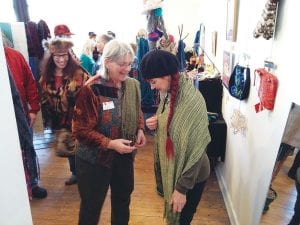 The Northwoods Fiber Arts Guild was a great place to shop on Saturday, December 6. Left: Visitors to the Christmas Open House at the Grand Marais Art Colony were also able to see a variety of demonstrations, such as hand knitting with Maxene Linehan. Middle: Linda Chappell helped at the hands-on craft table, making delightful little Christmas gift pockets. Right: Fiber artists were on hand to help shoppers find the perfect item, like this lovely shawl.