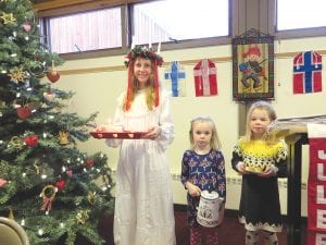 Left: St. Lucia (Elsa Lunde) was accompanied by Ella Hallberg and Piper Sporn at the Julefest celebration held December 13 at the Bethlehem Lutheran Church in Grand Marais. Below: Wearing her red Scandinavian sweater, June Olsen, well past her 90th birthday, was at the church bright and early setting tables with plates filled with sweet treats for the bake sale. Below left: Gwen Lenz and Jody Daugherty (right) were two of the many Bethlehem Lutheran women who worked hard to make the bake sale at the Julefest so successful. Proceeds from the sale are put into various programs and activities sponsored or run by the church.