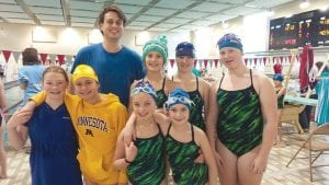 Some of the YMCA swim team celebrating poolside. (L-R, front) Malin Anderson, Louise Ramberg, Grace Blomberg, Lexi Surbaugh. (L-R, back) Coach Cody White, Ella Hedstrom, Aurora Schelmeske, Chloe Blackburn.