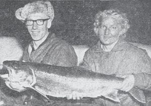 According to the information provided in the April 15, 1965 News-Herald, this photo shows proof of three things: that the big ones don’t always get away; that there are some big ones left in the inland lakes; and that Tumsey Johnson, who caught this 20-pounder, is an expert fisherman. His main problem was to squeeze the fish through the 6-inch hole in the ice. Here Mr. and Mrs. Johnson are proudly showing their prize catch.