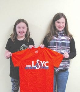 Bridget Cooley (left) and Amy Carpenter display the shirt they were given to wear when they performed with the Lake Superior Youth Chorus Honor Choir.