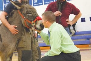 Above: “Winning” the contest to see who raised the most money, Principal Adam Nelson plants a kiss on a donkey’s nose. An anonymous school staffer donated $150 if Superintendent Beth Schwarz and Principal Gwen Carman also gave the donkey a kiss. They all did! Left: Brenna Hay had the ball several times, but her donkey didn’t want to go in the right direction.