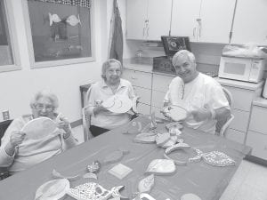 Residents at the North Shore Care Center have been busy painting whimsical wooden fish for their Spring Fling Sale coming up in May. (L-R) Bernice LeGarde, Lorraine Wipson, and Randall Boyd, a volunteer/instructor.