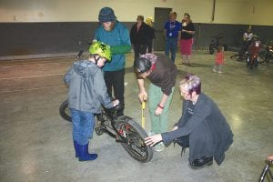 The annual Bike Safety Rodeo was held May 7 at the Cook County Community Center in Grand Marais. Despite some rain showers, children of all ages came with bikes and helmets and had them inspected and adjusted if needed. Kids also pedaled through a wiggly course with stops along the way and were given stickers by volunteers from law enforcement personnel. Commissioner Heidi Doo-Kirk and bike rodeo volunteers help a youngster with his bike inspection.