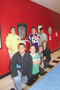 Above: Biidaash Aubid with his colorful painting, in remembrance of his uncle. Left: The talented sixth-grade artists are (L-R, front) Jacob Paro, Biidaash Aubid, Jack Wilson, and Art Instructor Belle Janicek. (L-R, back) Raina Christianson, Jered Paro, Angel Burnett. (Not pictured Ariana Poyirier)