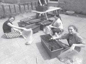 Some Middle School students from School District 166 helped clean up the backyard patio at the Care Center on Service Day in May. (L-R) Mia Westerberg, Lupita Mendivil, and Julianna Porter.