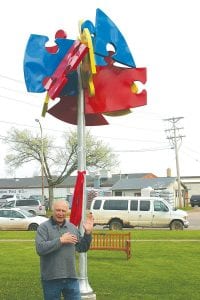 Above: Tom Christiansen talks about the process he used to build the colorful art piece that stands behind him. Left: Grand Marais Mayor Jay Arrowsmith DeCoux cuts the ribbon, held by Cook County High School student Sam Kern and Chris Magnusson, coordinator for the Arrowhead Library System Legacy Funds.