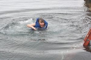 Right: Brrr! Pastor Kris Garey heads for shore after taking a leap off the Hovland dock.