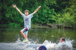 With the log spinning madly, churning white water, Dominic Wilson throws up his hands to catch his balance while his competitor landed in the drink. Wilson finished third in the U-13 boys log rolling division at the Three Rivers Roleo log rolling tournament held in Onalaska, Wisconsin on July 11.