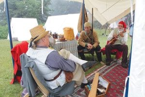 Many re-enactors return to the Grand Portage National Monument Rendezvous Days year after year, just as the voyageurs of the past did. These fellows spent some time catching up at one of the 142 campsites on the grounds. Right: Hauling water is just one chore for young re-enactors.