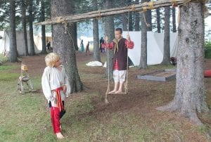 Left: The playground, voyageur style. Middle: There are many demonstrations of 18th century occupations, such as silversmithing. Right: A modern-day tourist meets a child from the past. Anna Patterson of Thunder Bay shows AnnaBelle Silence of Grand Marais her interesting—low-tech—game.