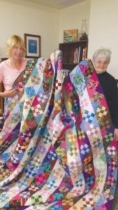 Cook County Higher Education Director Paula Sundet Wolf (left) and quilter Carol Harris display the stunning quilt created by volunteers. The “Just Another Nine Patch” quilt is being raffled to build funds for the Nancy and Mike Carlson Scholarship Fund.