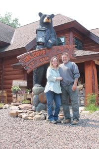 Above: Andy and Ida DeLisi in front of their lodge—and the big bear that welcomes visitors. Right: The massive stone fireplace created from native stone is the centerpiece of the main lodge building, surrounded by comfortable couches. Far right: Each cabin has its own distinctive touches, but all are welcoming.