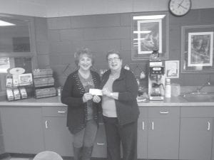 Above: During Rendezvous Days, Grand Portage Elder Corky Stevens' daughter Michelle (left) sold T-shirts with a lovely design made by her mother of the Witch Tree. Michelle donated a portion of the sales to the ENP. She presented the check to ENP Director Patty Winchell-Dahl who said the money will be used to replace the ENP commercial can opener. Left: ENP Head Cook Polly James, Wisdom Steps Aide Carol Hackett and Chore Worker Shirley Stevens shelling fresh beans and peas from the gardens for meals at the ENP.