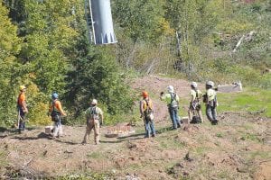 A ground crew from the ski lift company Doppelmayr watches as the Sikorsky S-61 helicopter slowly lowers a tower pipe into place. Once the pipe was close enough workers swung the tower onto the foundation and quickly bolted the 8,000-pound tower into place.