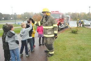 Above: High fives for firefighters! Students at Great Expectations School and Sawtooth Elementary School enjoyed a visit from the Grand Marais and Maple Hill Fire Departments on Thursday, October 8. After showing students the equipment on the fire truck, firefighter Matt Conlin got high fives from the kids. Right: Everyone got a chance to try out the big fire hose. Kyle Monson helped this young man aim for a tree on the school lawn. The visit also included a fire safety talk in the classroom.