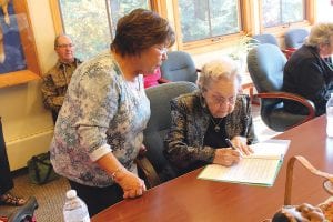 Above: Making it official. Museum Director MaryAnn Gagnon watches as Iola Wojtysiak signs the paperwork to transfer ownership of the items to the museum.