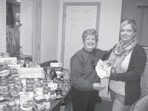 Cook County Food Shelf volunteer Gwen Lenz was delighted to accept the donations collected for the local food shelf by the Cook County Senior Center. Senior Center Program Director Jes Rodne, right, presented almost $600 in cash and 550 pounds of food and household items.