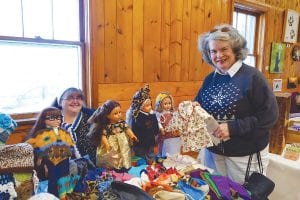 The Hovland Arts Festival was also the scene of holiday merriment on Saturday, November 26. Mary Petz admires the doll clothing made by Valita Bockovich. Her handiwork will delight some little girls this Christmas.