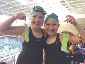 Happy swimmers Grace Blomberg and Liv Hedstrom show off their ribbons for their successful heat.