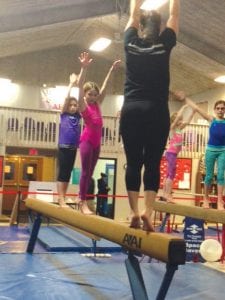 Gymnasts from Cook County traveled to Duluth on December 12 to meet other gymnasts and to take part in some fun training. Carefully watching a Duluth instructor (in foreground) are (L-R) Emma Crook, Claire Lindstrom, Elsa Sorenson and Anna Hay.