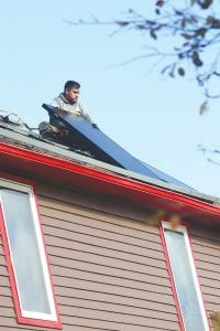 A worker for the All Energy Solar Company carefully placed a panel onto the roof of the Art House B&B. It took the company about two days to install the panels.