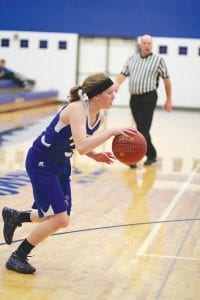 Above: In a recent home game, senior forward Shauna Blake looks to make a nice pass as she dribbles towards the basket. Right: As always, Viking players stand at attention for the National Anthem before every game.