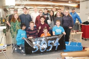 Above: Taking a break from fine-tuning their robot, the Cook County Schools Robotics team is (L-R, front) JRon Tamanaha, Lynden Blomberg, John VanderHeiden (front), David Blackburn, Adrian Howard-Larsen. (L-R, middle) Nina Woerheide, Lohnen Vondall, Noah Works, Jaden Aubid, Sarah Carman, Shae Morawitz. (L-R, back) Coach Tom Nelson, Sam Meyer, Andy Kern, Bergen Soland, Joseph James, Connor Franks, Caleb Phillips, Coach Daniel Henry. (Not pictured Isak Terrill, Jack Viren) Left: Bergen Soland, Jack Viren, Andy Kern, JRon Tamanaha and Isak Terrill work on the tracks for the robot.