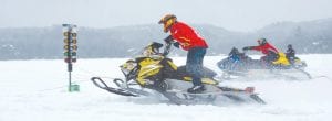 Above: Despite gray skies, Hungry Jack Lake was the place to be for racing fans on Saturday, February 20 for the Cook County Ridge Riders Snowmobile Drag Races. Colee Johnson (on the yellow Ski-Doo) and Josh McDonnell (on the blue Polaris) face off on the snowy ice drag track.