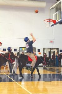 Donkey Basketball was “played” at the Cook County High School gym on February 18, benefitting the CCHS Band. Far left: Aaron Mielke of the Grand Marais Fire Department/Law Enforcement team makes one of several points he made for his team. Top left: Leo Johnson accidentally bopped his donkey on the rear-end with a basketball, so he had to apologize—with a kiss! Lower left: Jaret Baker struggles to hold onto the ball and stay on his energetic donkey. Top right: School Counselor Kris Hoffman and his teacher colleagues donned sombreros for the event. The donkeys were not impressed. Hoffman was a great sport, as were all the “players.” The teachers and law enforcement went to the “championship” and the teachers’ team won. To see more pictures of Donkey Basketball, visit http://www.cookcountynewsherald.com/image.