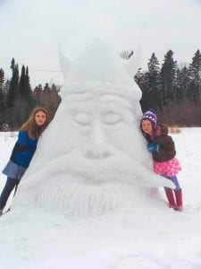 Lutsen has been invaded! Nina (left) and Siena Woerheide with the giant Viking head snow sculpture they created with their father, Dave Woerheide. Above: Lurking nearby is a giant snow shark.