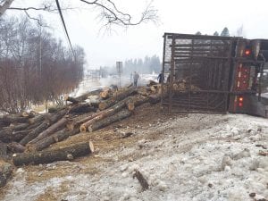 This fully loaded Peterbilt logging truck tipped over near the bottom of the Caribou Trail on Tuesday, March 8, spilling logs that hit a passenger car. Three people were injured in the crash.