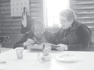 Doris Blank and Patty Winchell-Dahl looking at a historic photo, trying to figure out who is who in the picture.